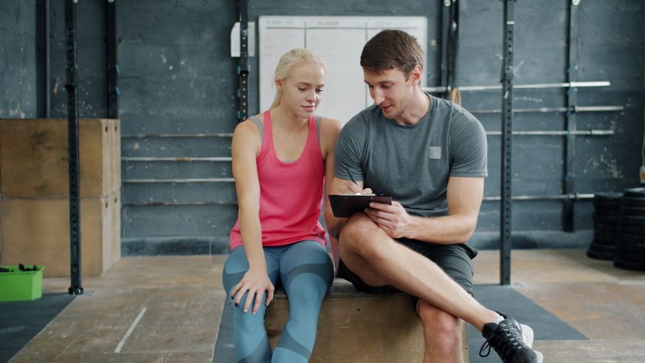 A personal trainer discusses workout plans with a client at a gym.
